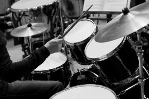 Hands of a man playing a drum kit in black and white